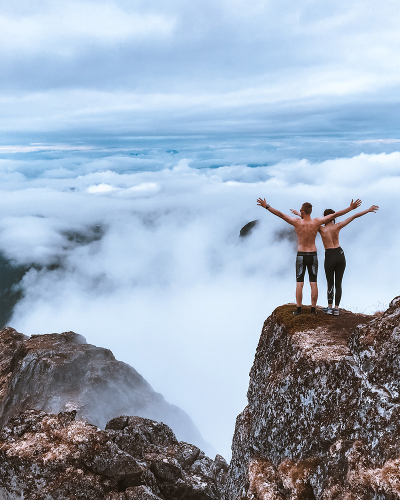 two people standing on top of a mountain with arms outstretched